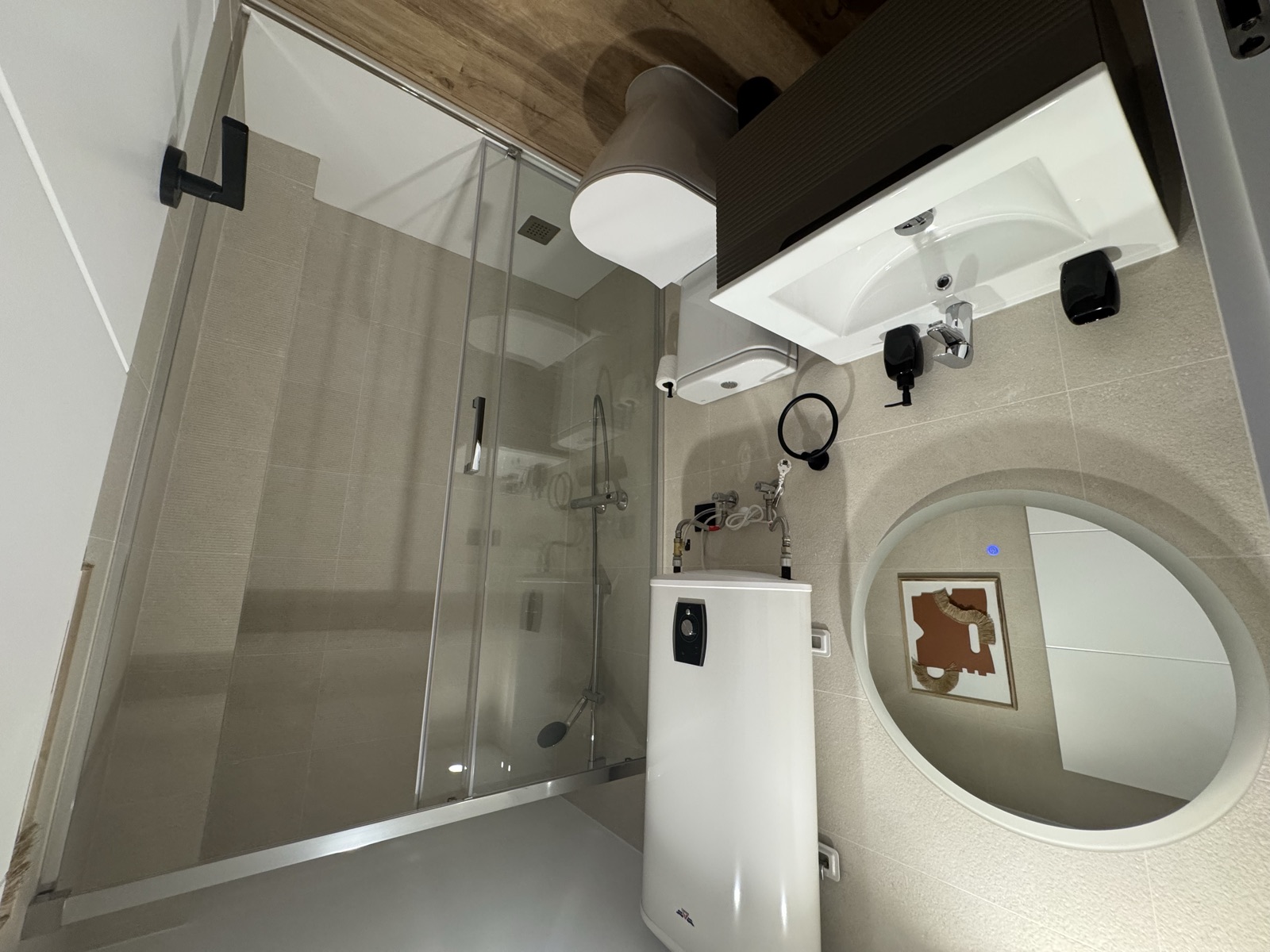 Baño en suite con ducha, lavabo y espejo redondo