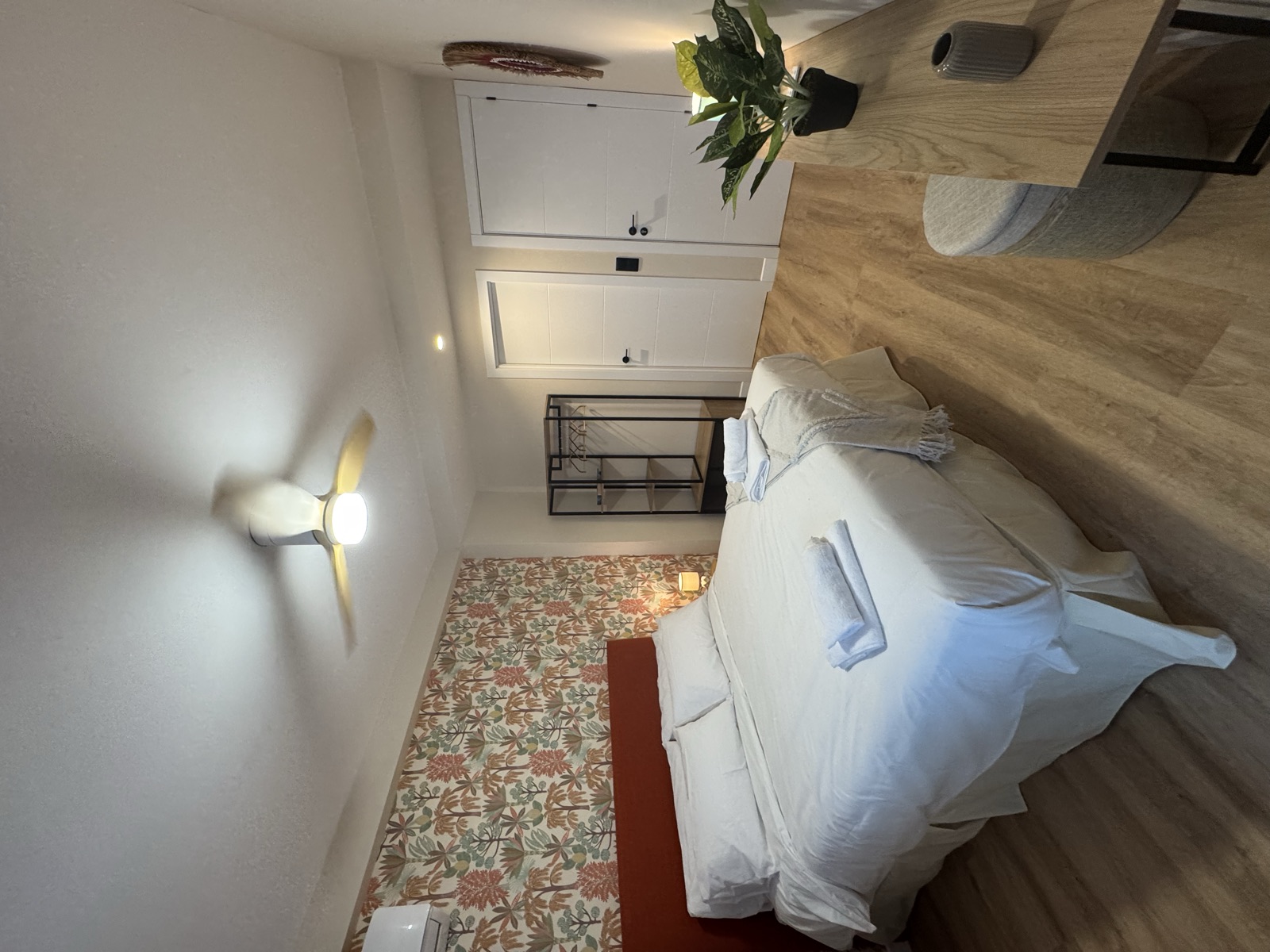 Suite con cama de matrimonio, papel pintado botánico y armario abierto