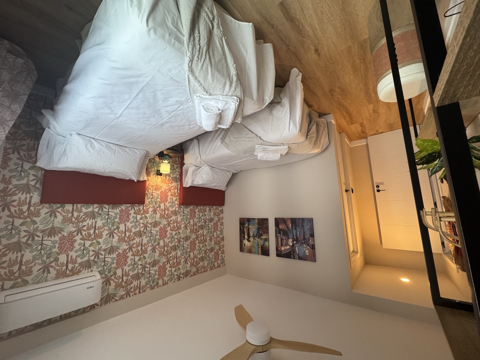 Habitación con dos camas individuales, cabeceros granate y papel pintado botánico