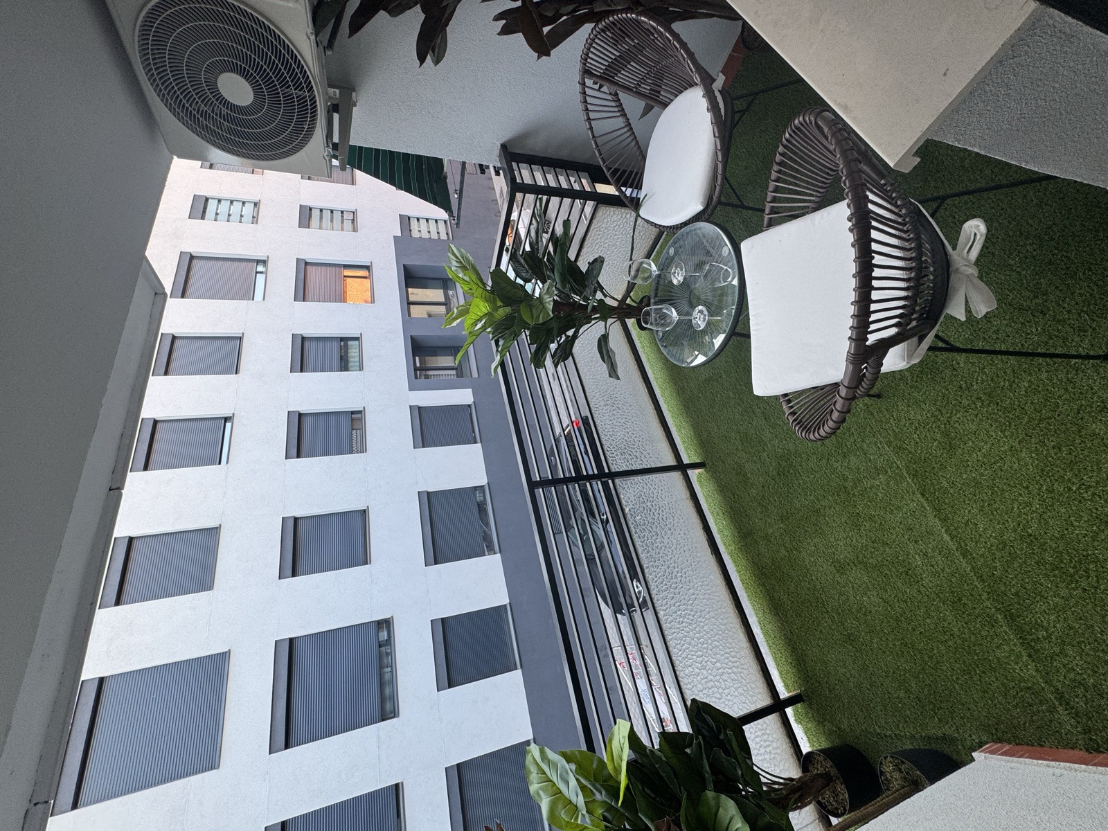 Terraza privada de una suite, con césped, mesa y dos butacas de fibra